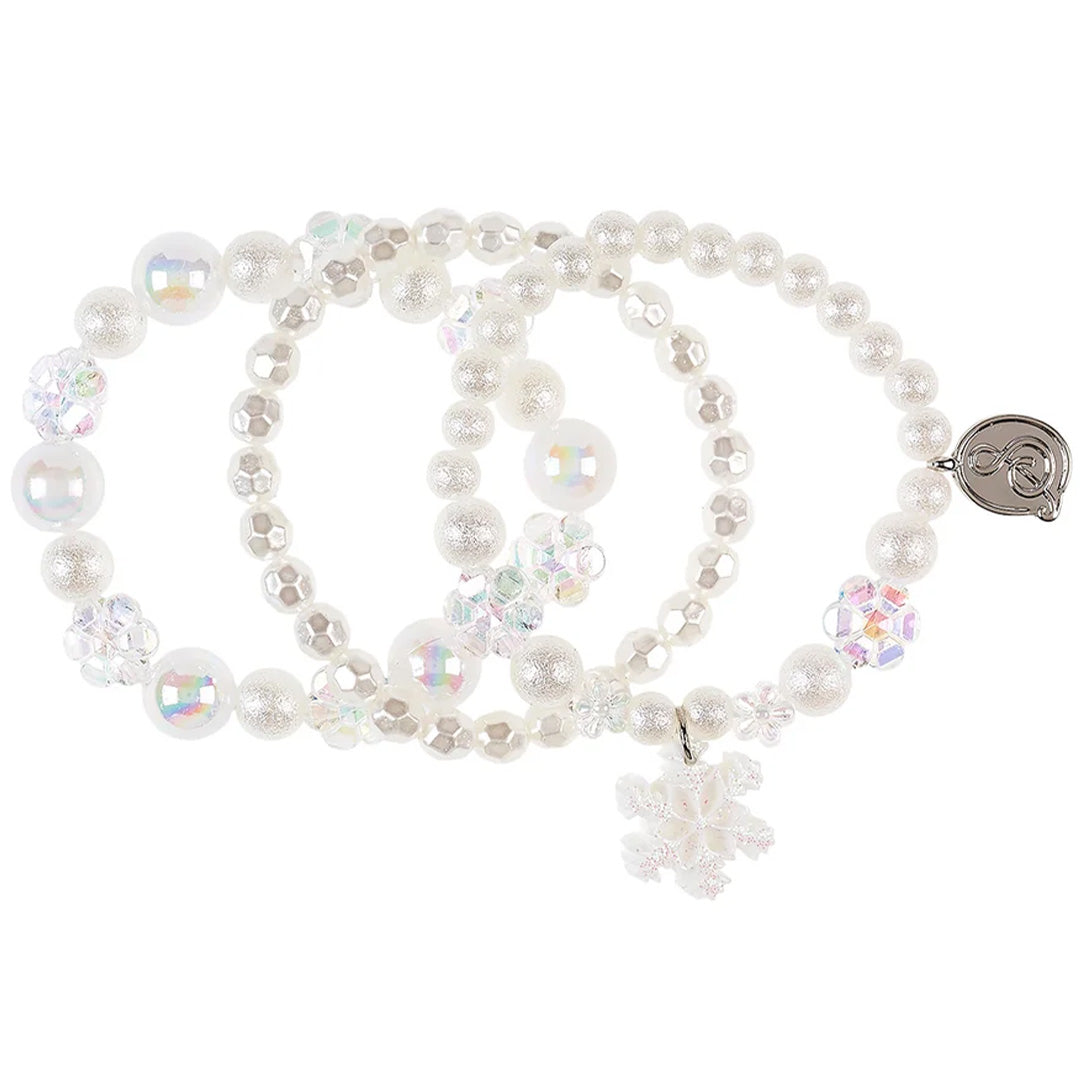 Drie witte Souza for Kids kinderarmbanden met parelmoer en iriserende kralen, waarvan één met een sneeuwvlok bedel, passend bij het kerstthema.