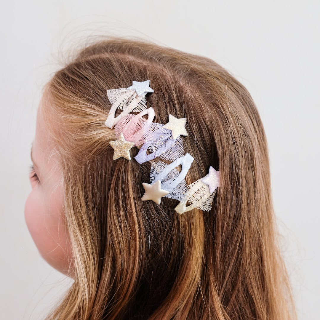 Detailfoto van een meisje met lang bruin haar dat mimi & lula haarclipjes met sterren draagt.
