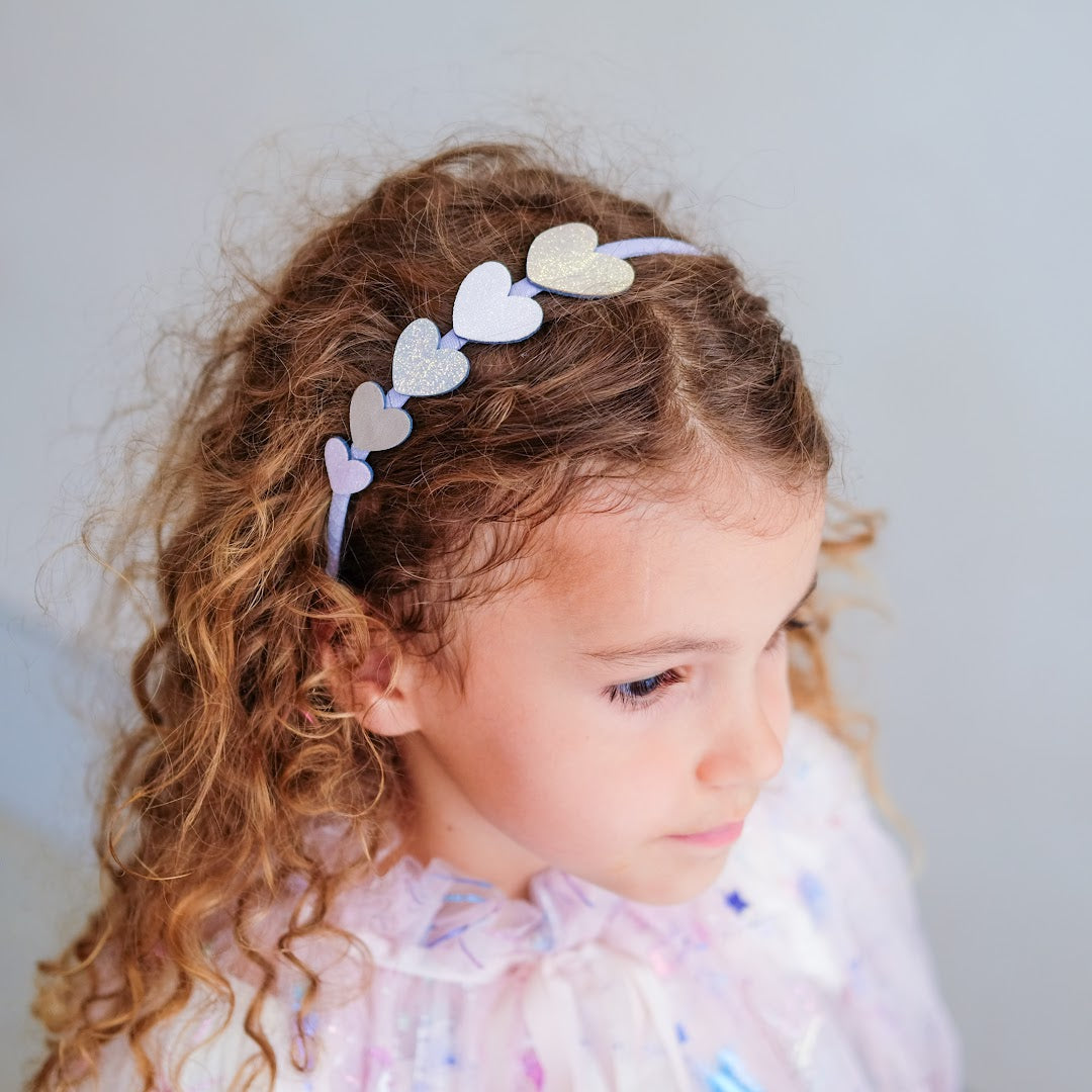Meisje met krullend haar draagt de mimi & lula diadeem met glitterharten.