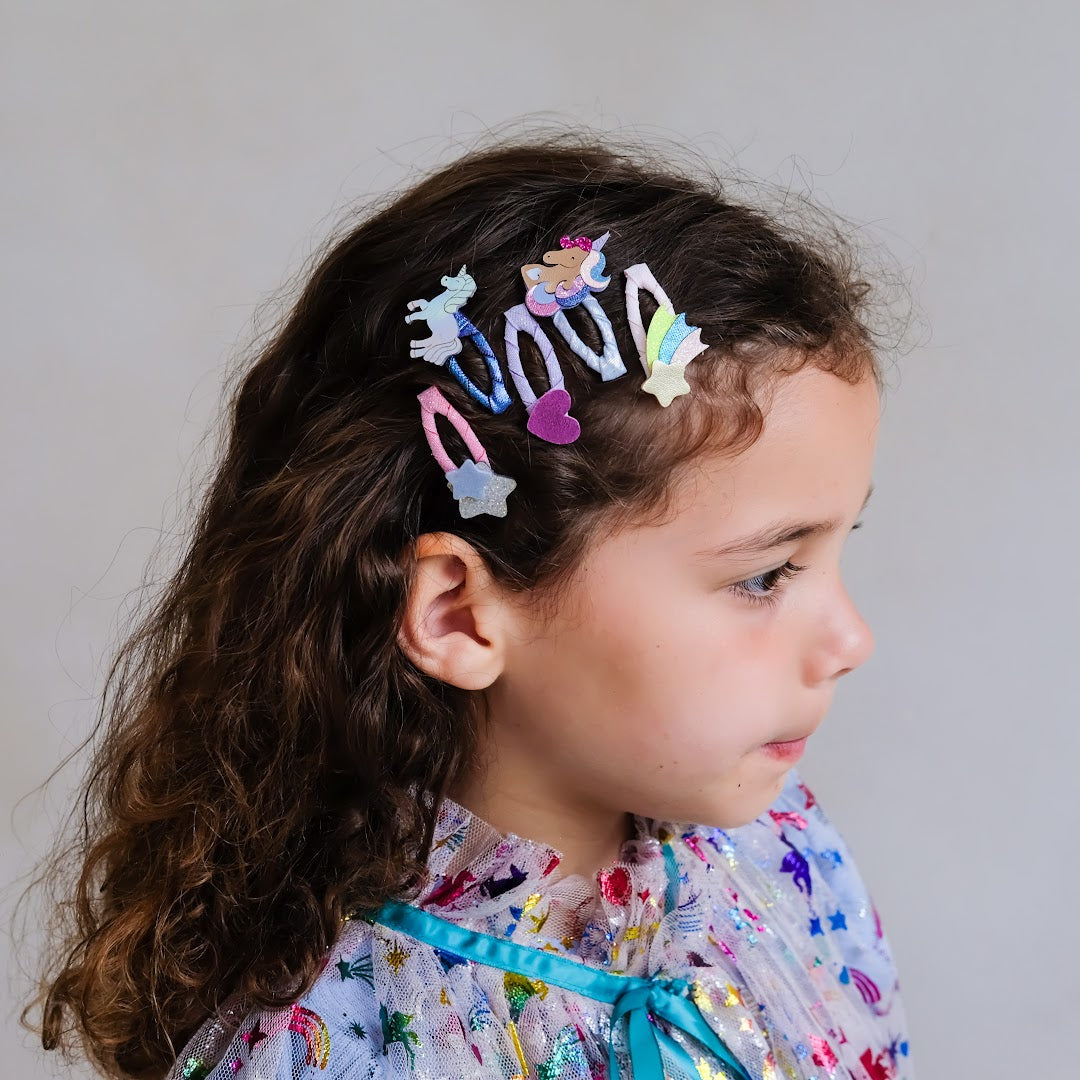 Meisje met krullend haar draagt Mimi & Lula kinder haarclipjes met eenhoorn en sterren.
