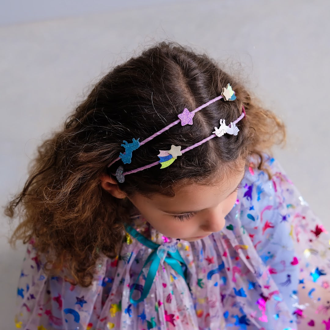 Een kind draagt de roze kinder hoofdband met eenhoorn en ster versieringen, van bovenaf gezien.
