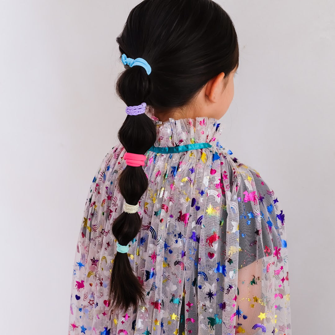 Een kind met lang donker haar, gestyled met kleurrijke haarelastieken.