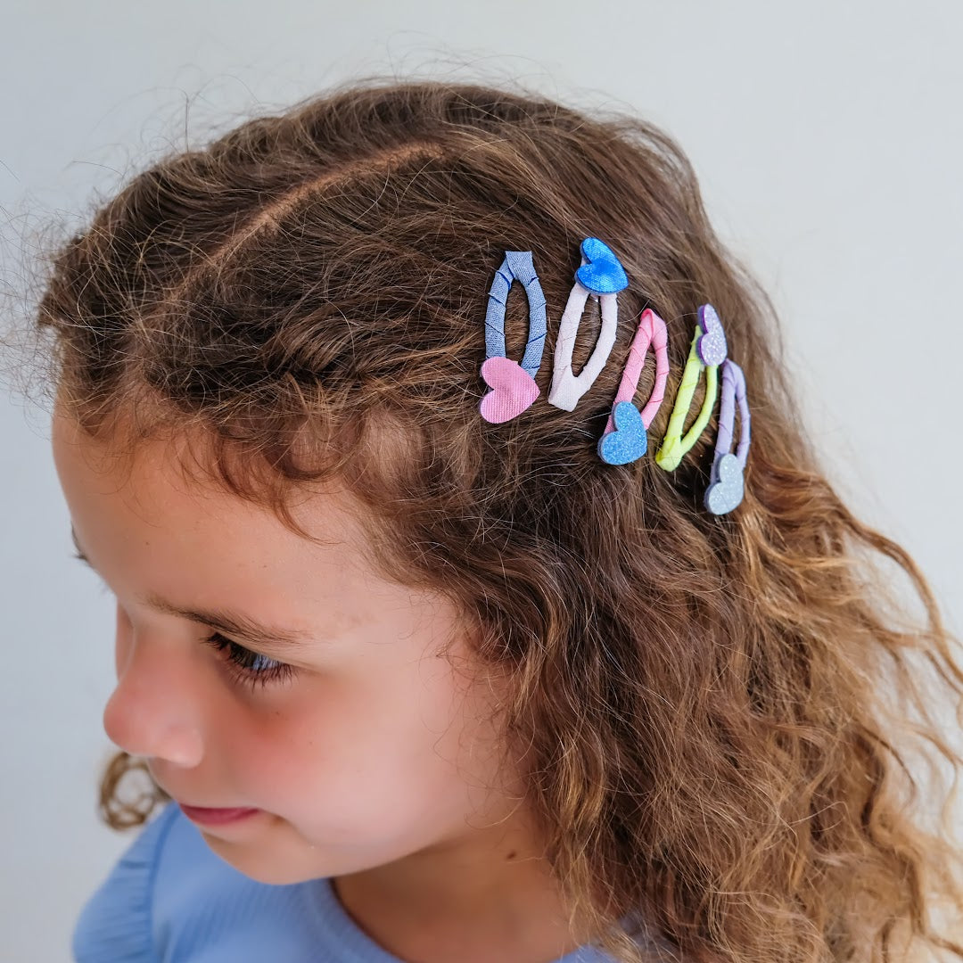 Een kind met bruin krullend haar draagt haarclipjes met harten.