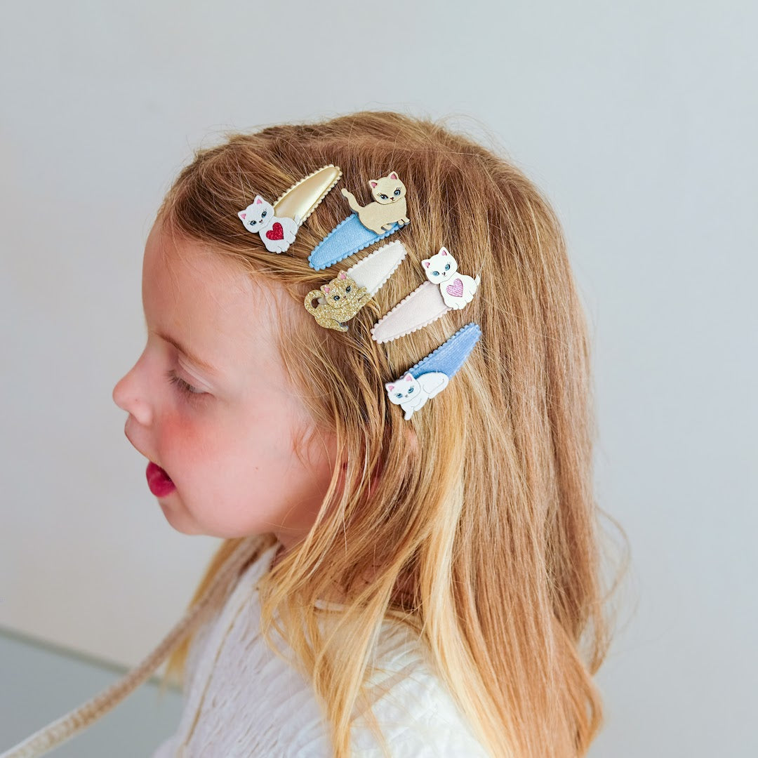 Een kind met blonde haren draagt diverse katten haarclipjes.