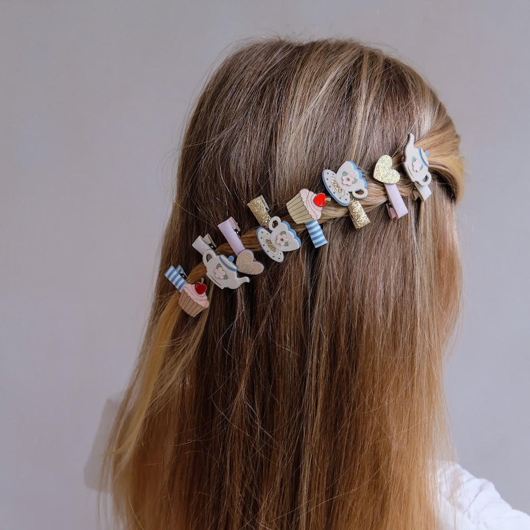 Een kind met lange, blonde haren draagt de mimi & lula haarclipjes met 'afternoon tea' thema als decoratie aan de achterkant van het hoofd.