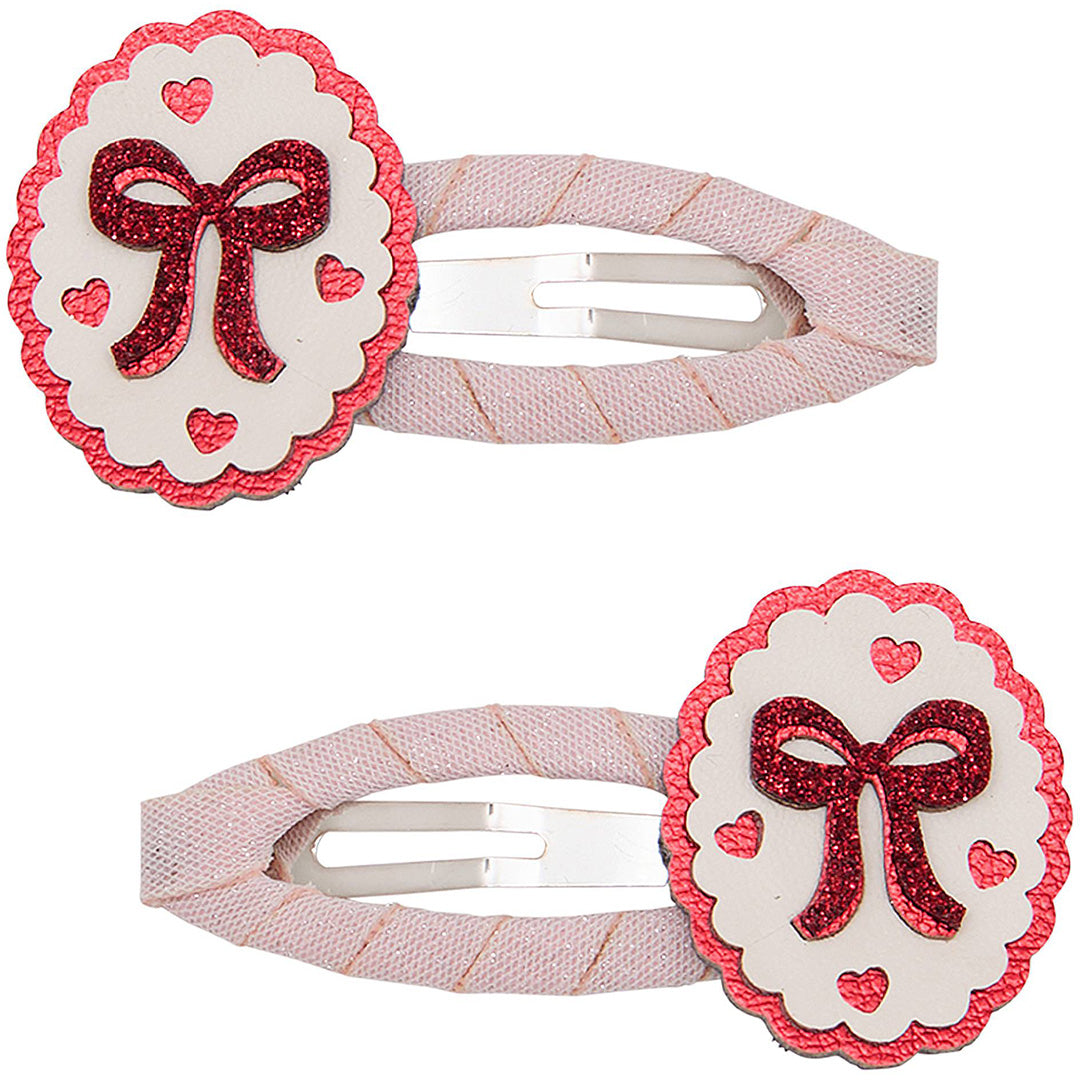 Twee mimi & lula haarclipjes met rood glitterstrikje en hartjes op een wit ovaal.