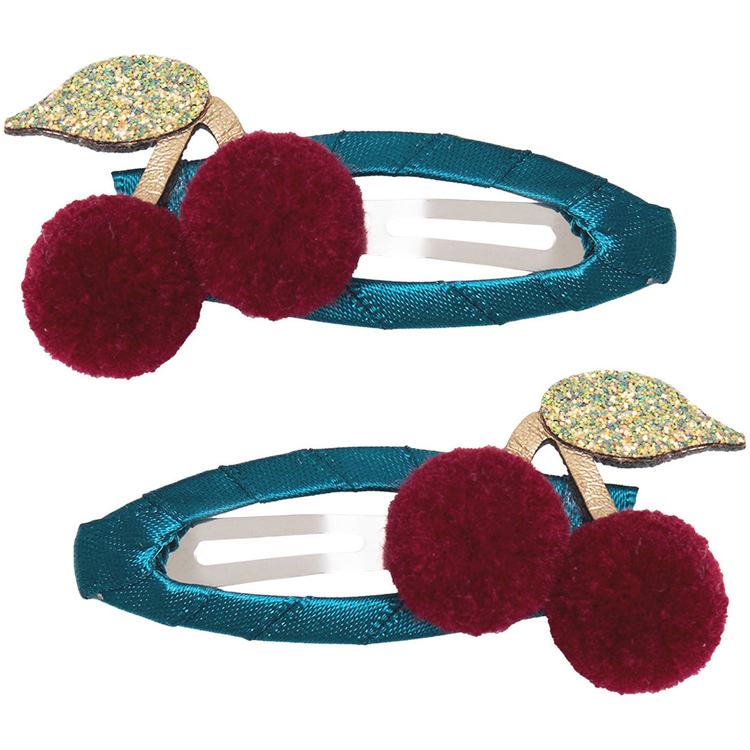 Twee mimi & lula haarclipjes met blauwe basis, rode pom-pom kersen en glitterende groene blaadjes.