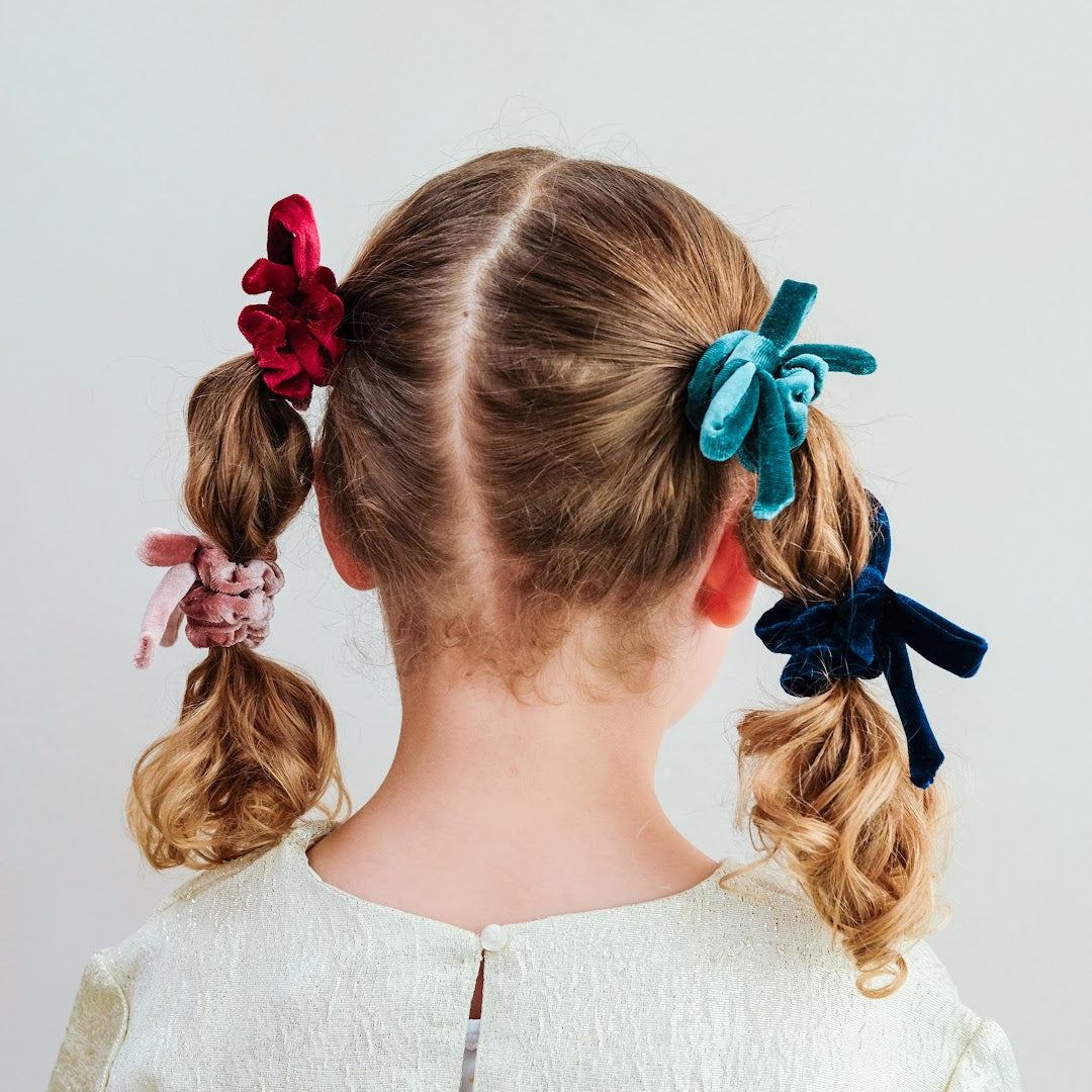 Achterkant van een kind met vlechtjes versierd met mimi & lula fluwelen scrunchies.