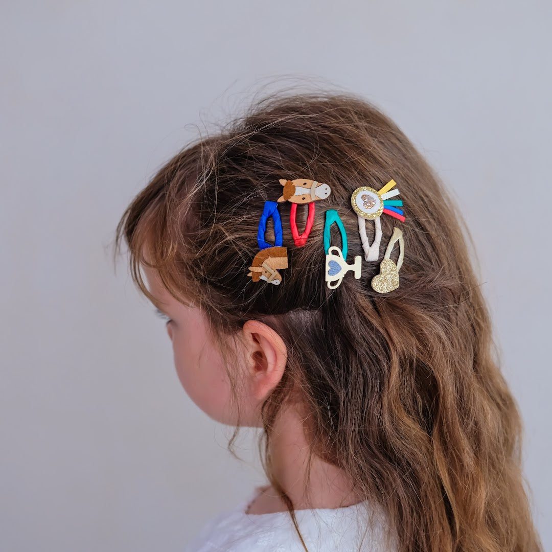 De mimi & lula kinder haarclipjes met paardenthema gedragen in het lange, bruine haar van een kind.