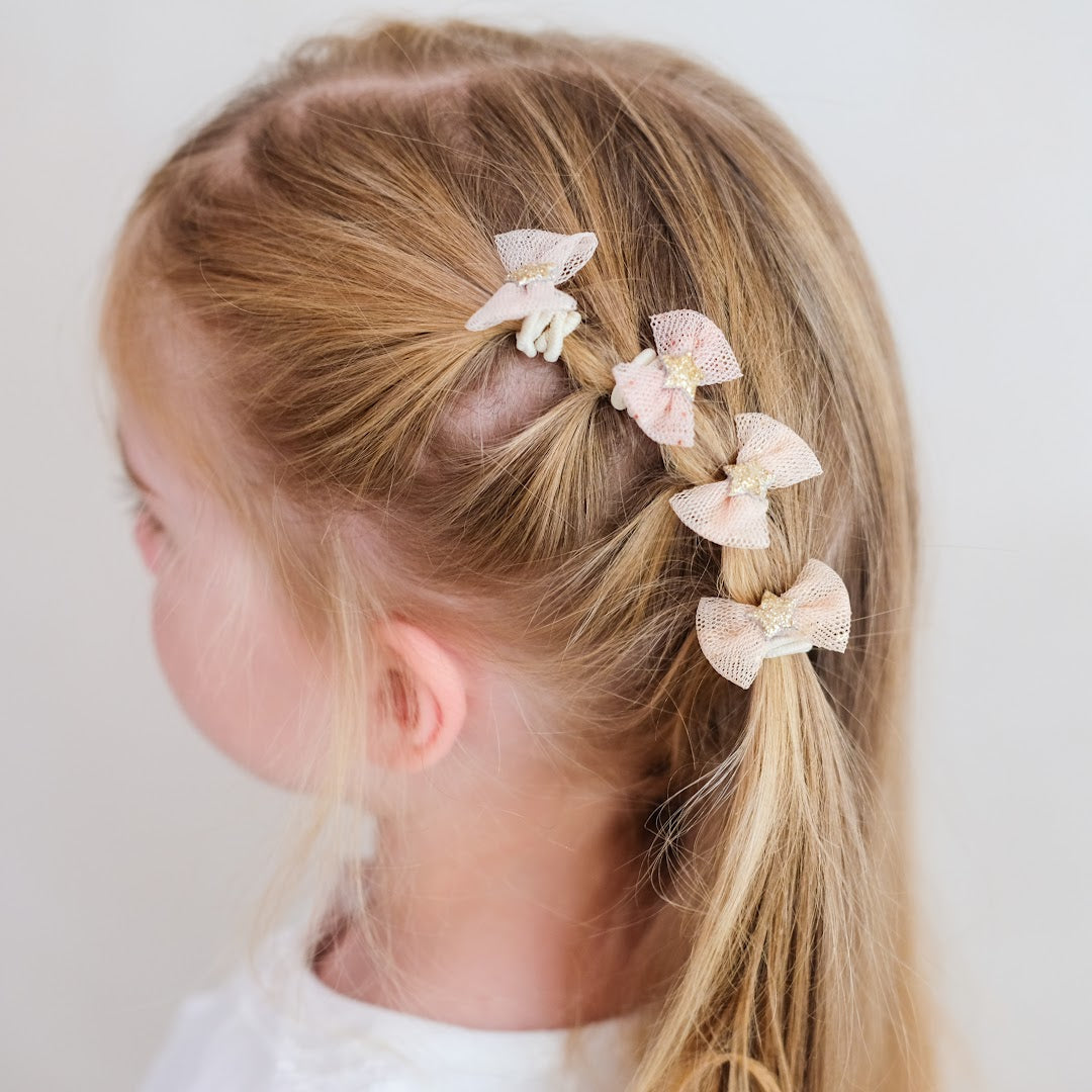 Een kind met blonde haren draagt vier mimi & lula mini tutu strik haarelastiekjes met sterren.