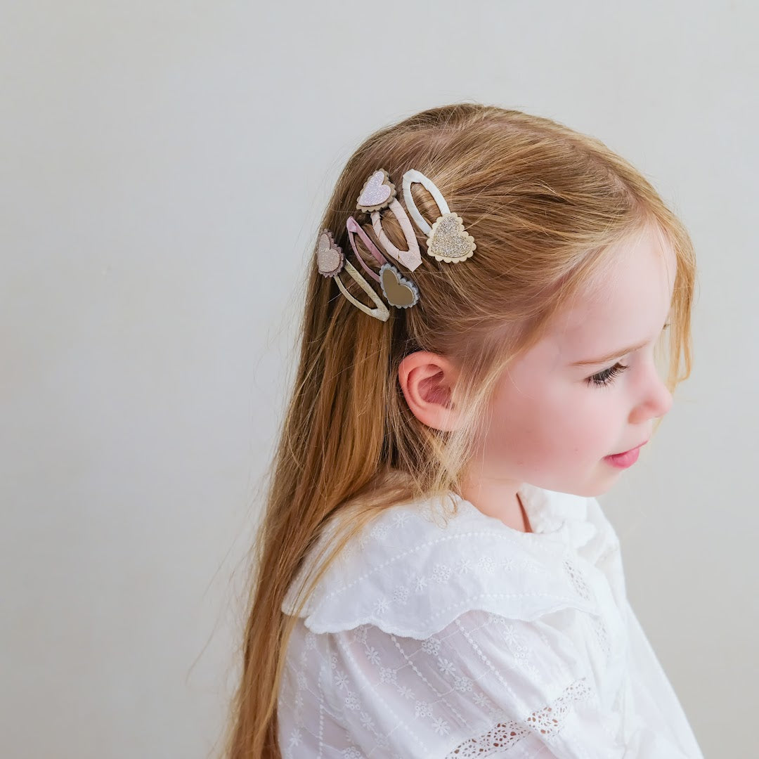 Een meisje met lang blond haar draagt de mimi & lula kinderhaarclipjes met hartjes.