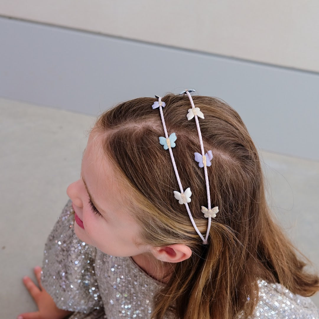 Een kind draagt de hoofdband met veelkleurige vlinders, van bovenaf gezien.