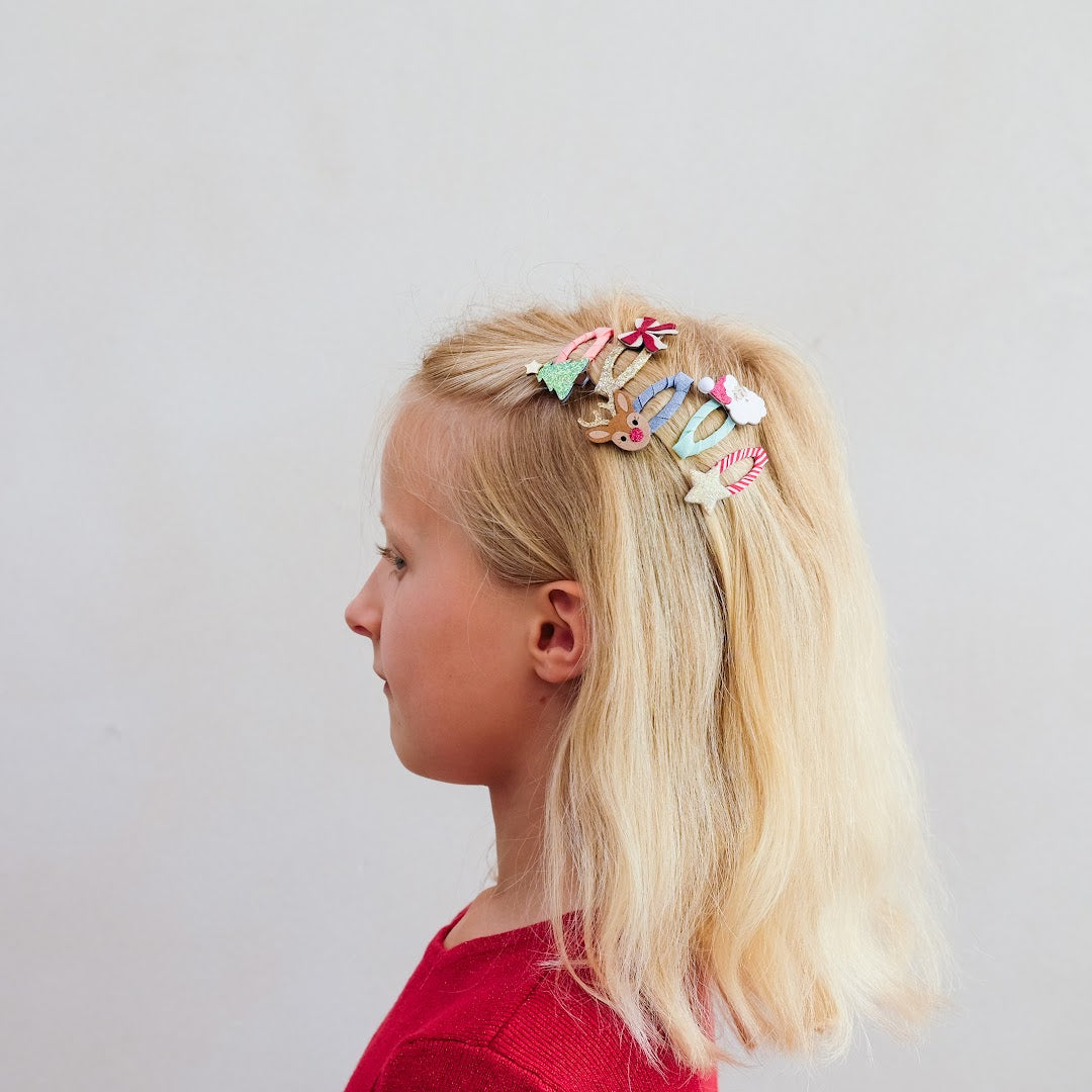 Een meisje met blond haar draagt de kerst haarclipjes in haar haar, gezien van de zijkant.