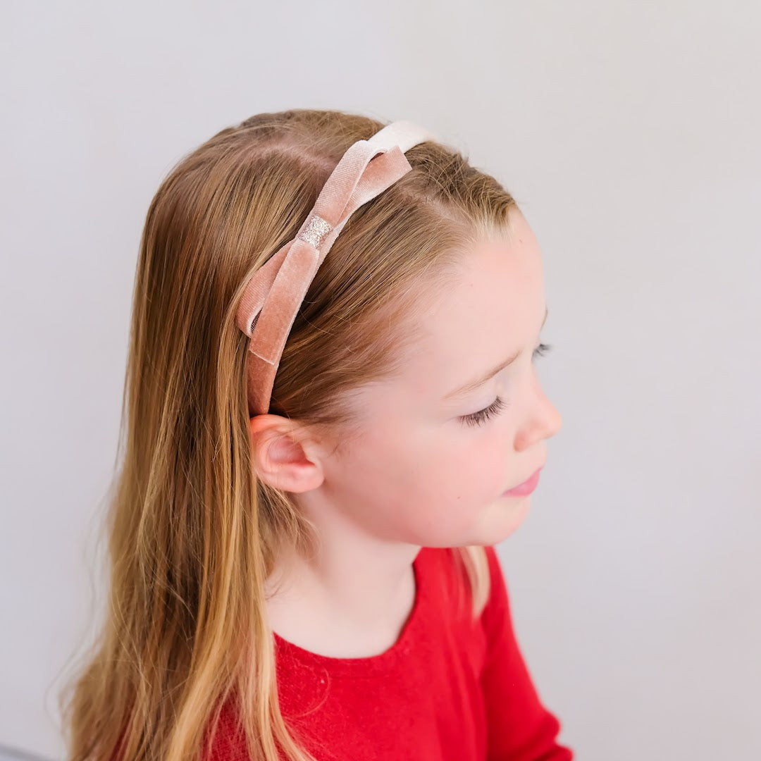 Zijaanzicht van een meisje dat de Mimi & Lula roze fluwelen kinderhaarband draagt.