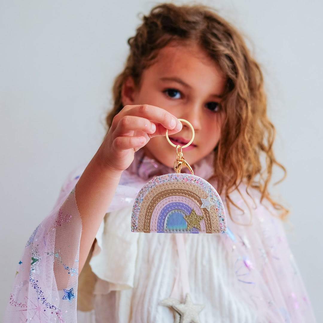 Een kind toont de Mimi & Lula regenboog sleutelhanger met sterren.