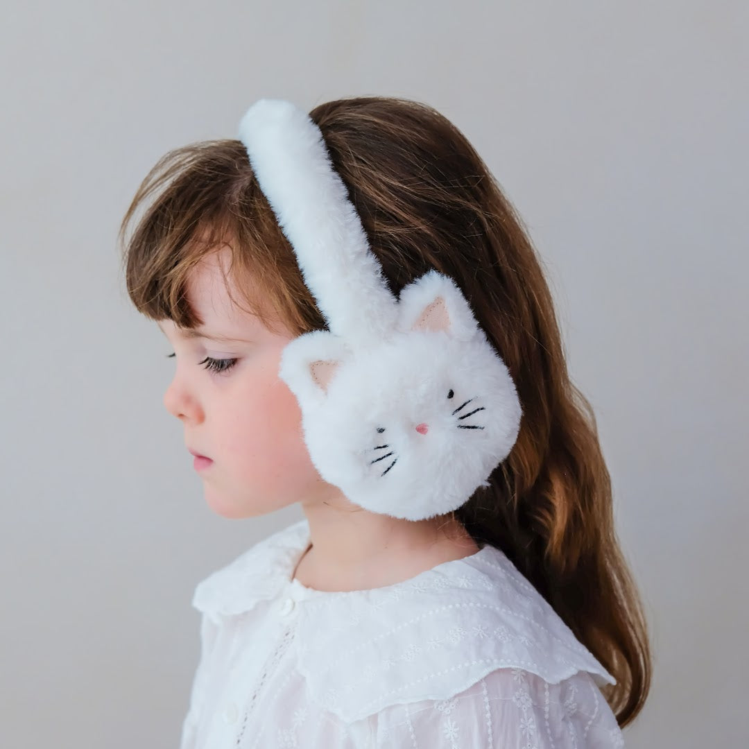 Een meisje met lang bruin haar draagt de witte pluche kattenoorwarmers.