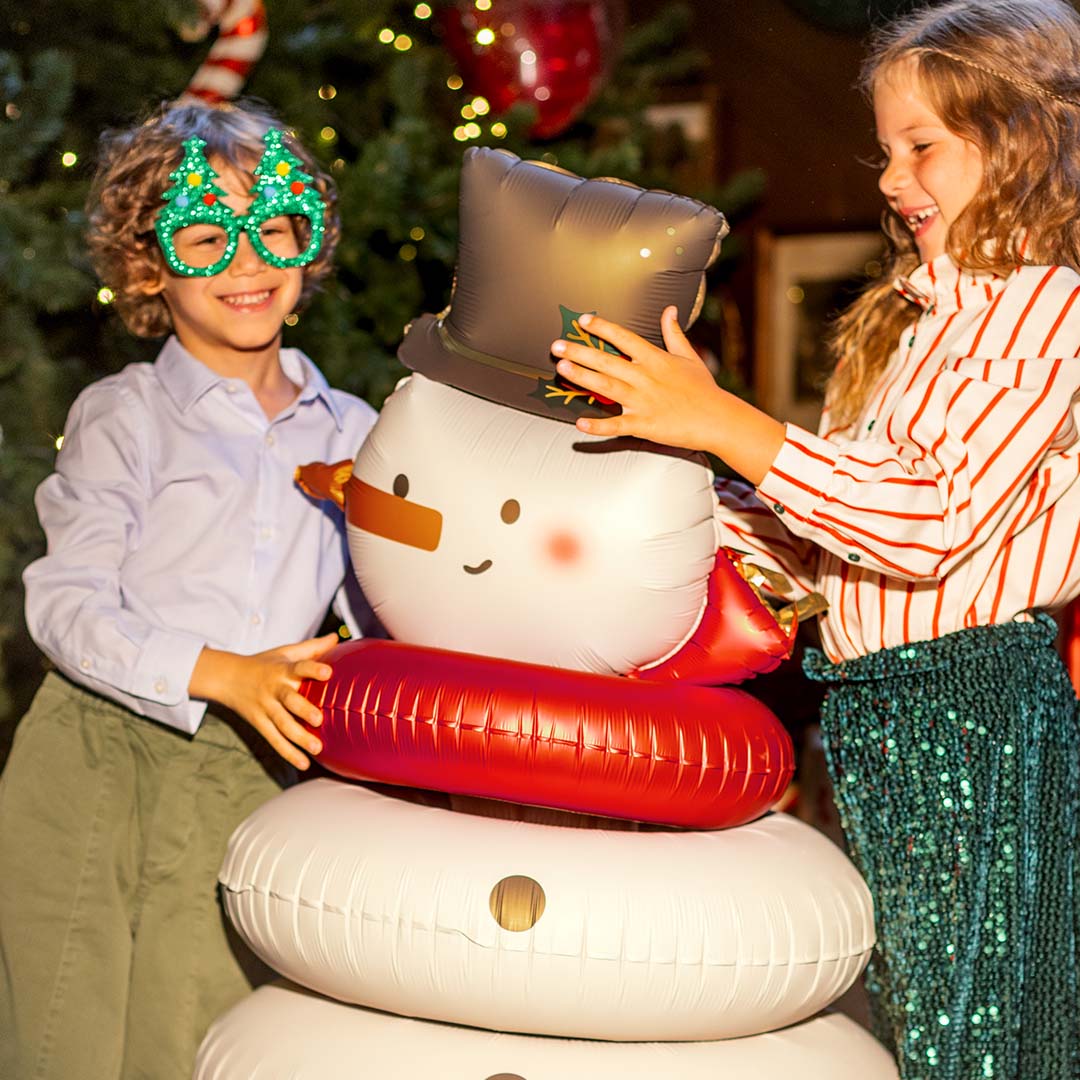 Twee kinderen lachen terwijl ze de Partydeco folieballon sneeuwpop aanraken.