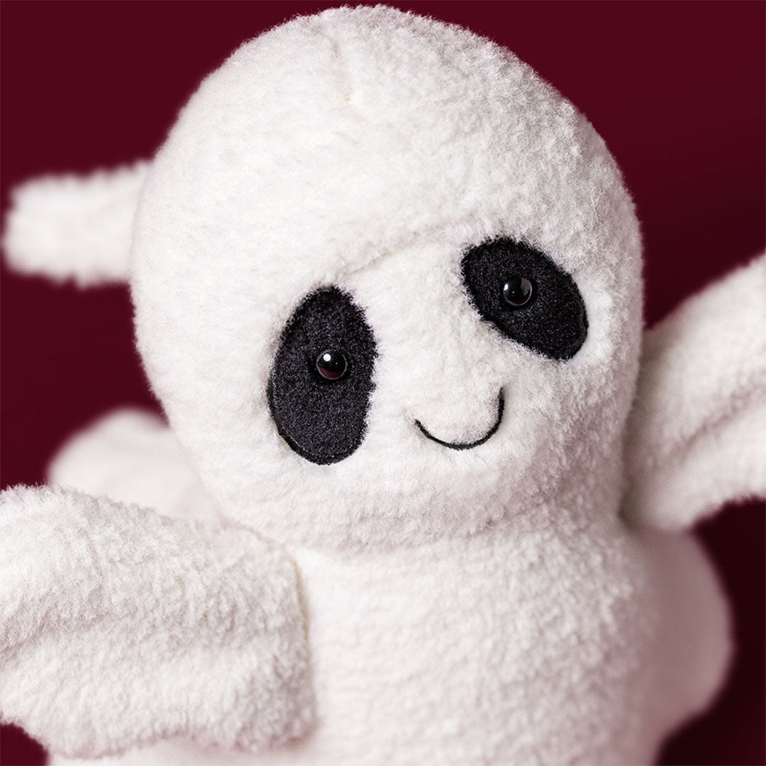 Detailopname van het gezicht van het Jellycat pluchen spookje met zwarte ogen en een glimlach.
