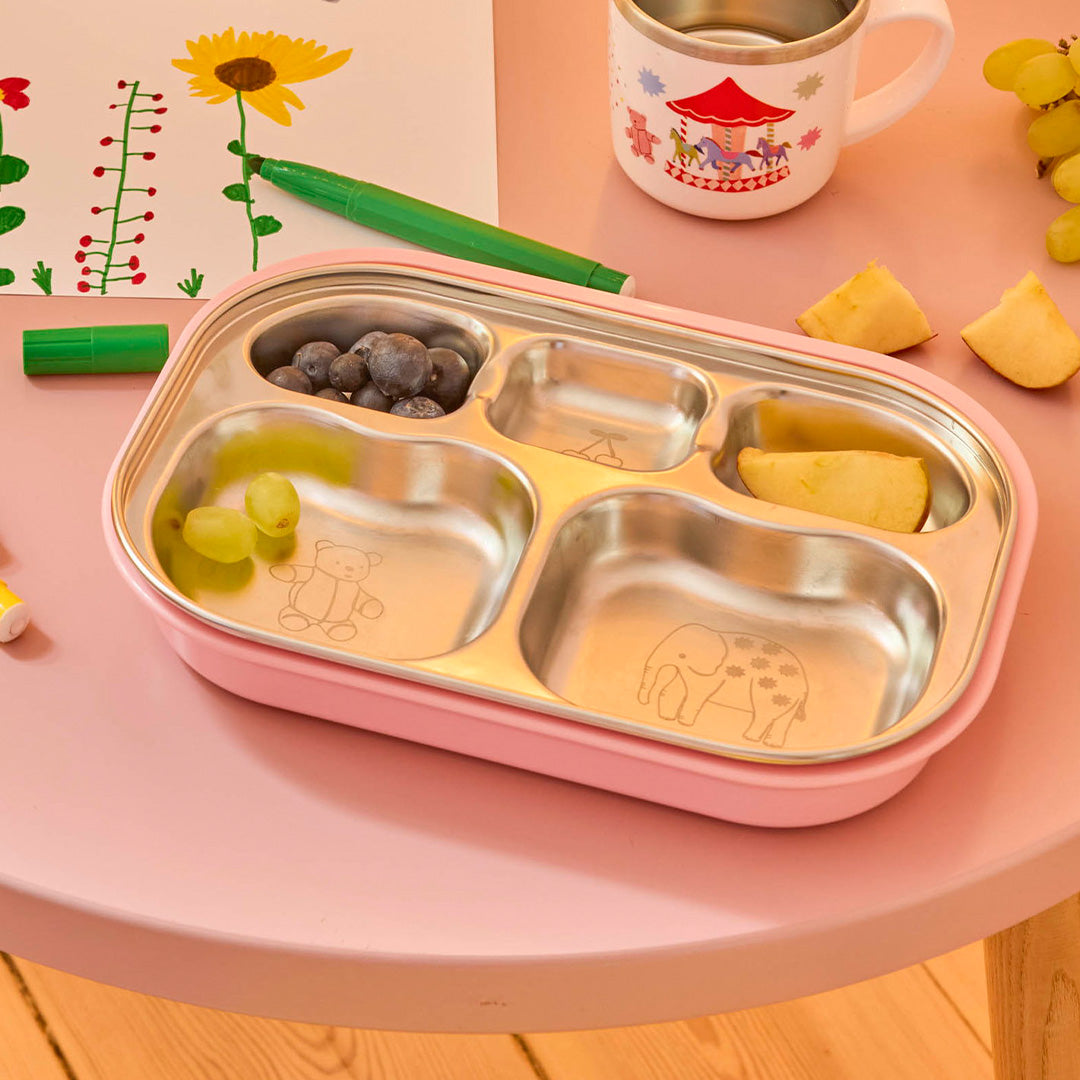 rice rvs vakjesbord in roze houder gevuld met fruit op een roze tafel.