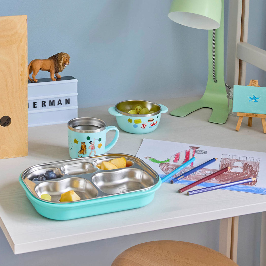 rice RVS vakjesbord met mintgroene onderkant gevuld met fruit op een bureau.