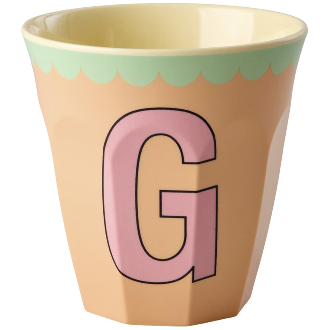 Rice plastic beker in perzik met een roze letter G en groene geschulpte rand.