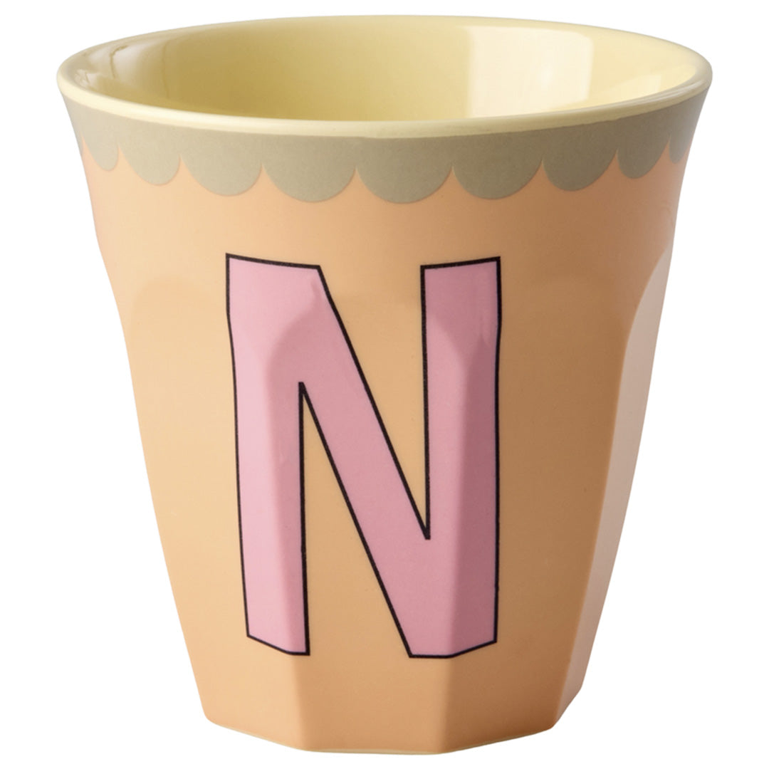 rice alfabetbeker met de roze letter N op een perzikkleurige achtergrond.