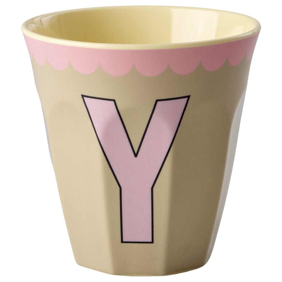 rice alfabetbeker met roze letter Y en een roze geschulpte rand op een beige achtergrond.