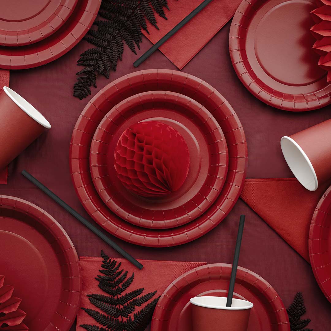 PartyDeco donkerrood plastic tafelkleed met daarop diverse rode feestartikelen.