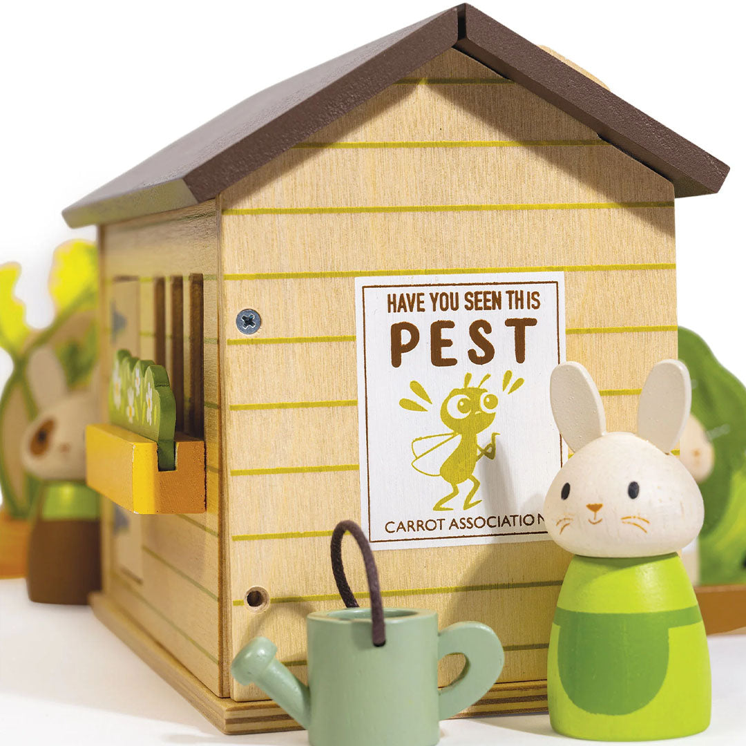 Detail van de houten schuur van de Tender Leaf Toys konijnen moestuin speelset met een poster en een konijnenfiguur.