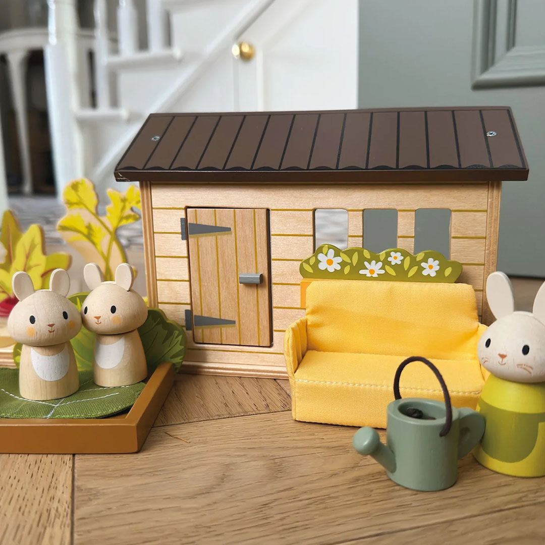 Detail van de Tender Leaf Toys konijnen moestuin speelset met de houten schuur, een bankje en konijnenfiguren.
