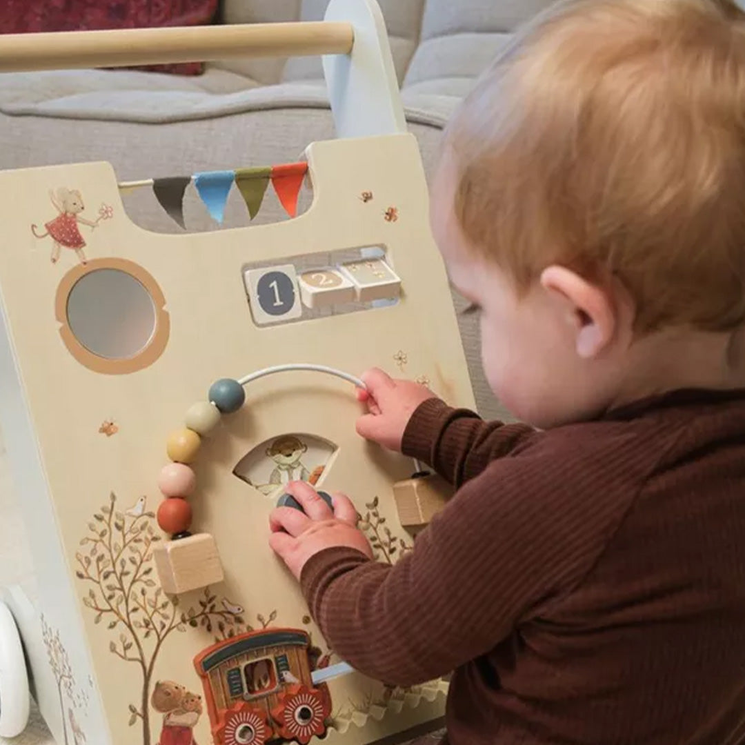 Een baby speelt met de kralen en draaischijf op de Egmont Toys houten activiteiten loopwagen.