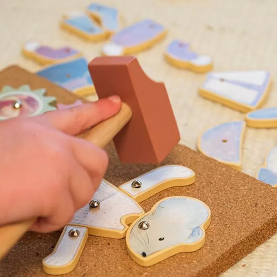 Een kinderhand hamert een houten muisfiguur vast op de kurkplaat van het Egmont Toys hamertje tik speelgoed.