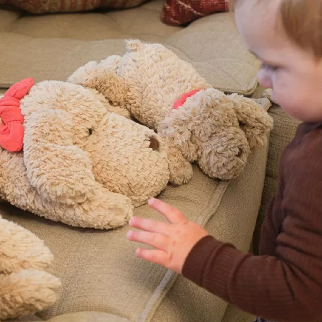 Een kind reikt naar een Egmont Toys pluchen knuffelhond Gabi die op een bank ligt.