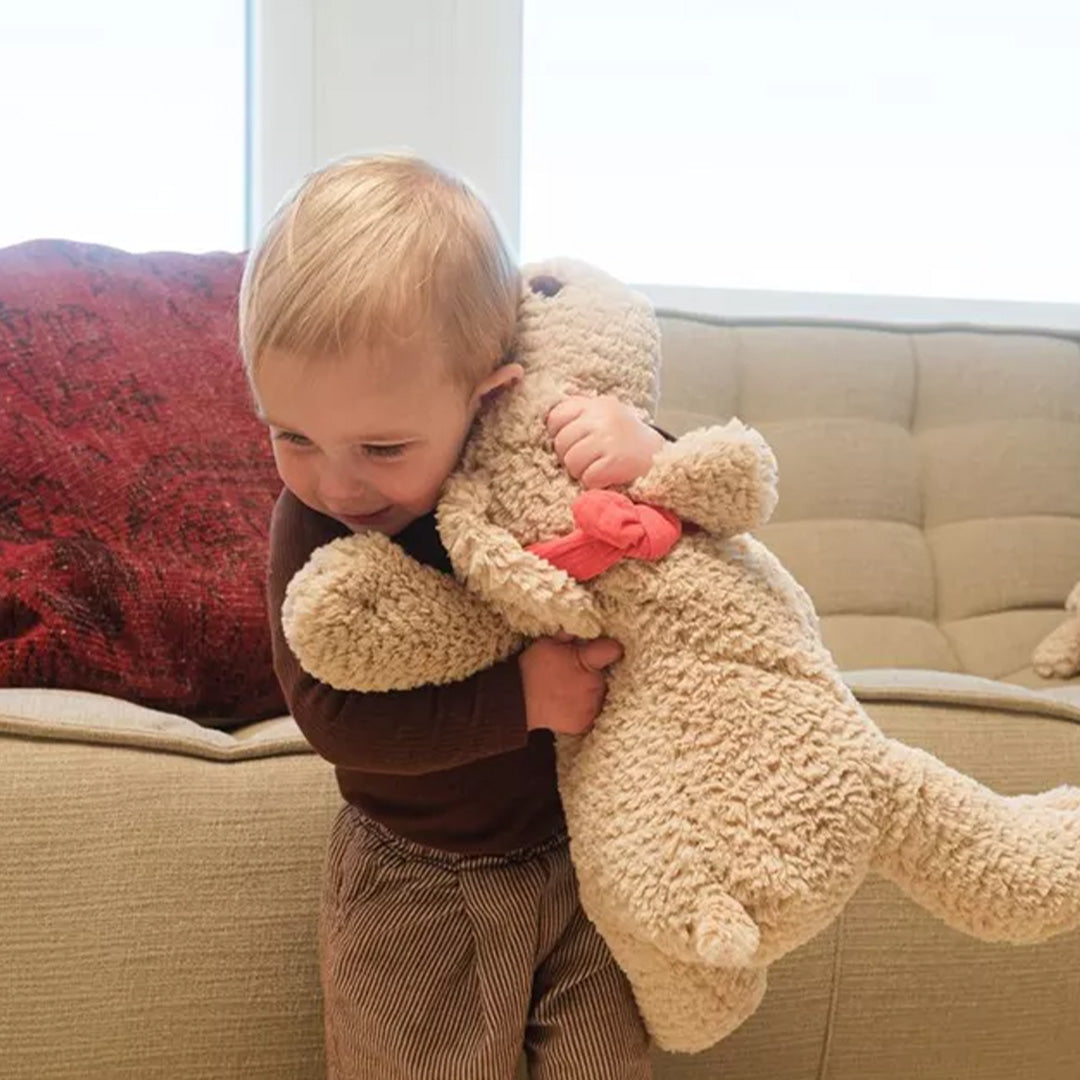Een lachend kind knuffelt de beige pluchen hond Gabi.