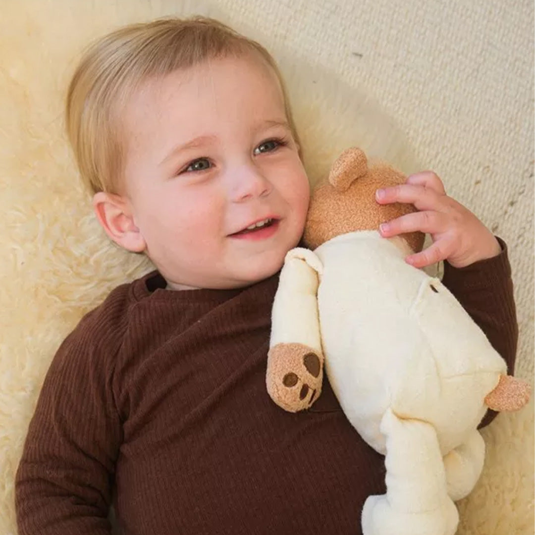 Een lachend kind knuffelt de Egmont Toys verzwaarde pluchen beer.