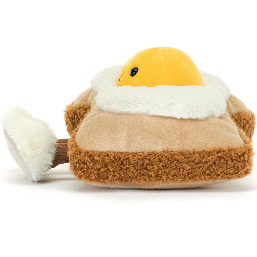 Jellycat Amuseables knuffelei op brood, van de zijkant gezien, met een uitstekend voetje.