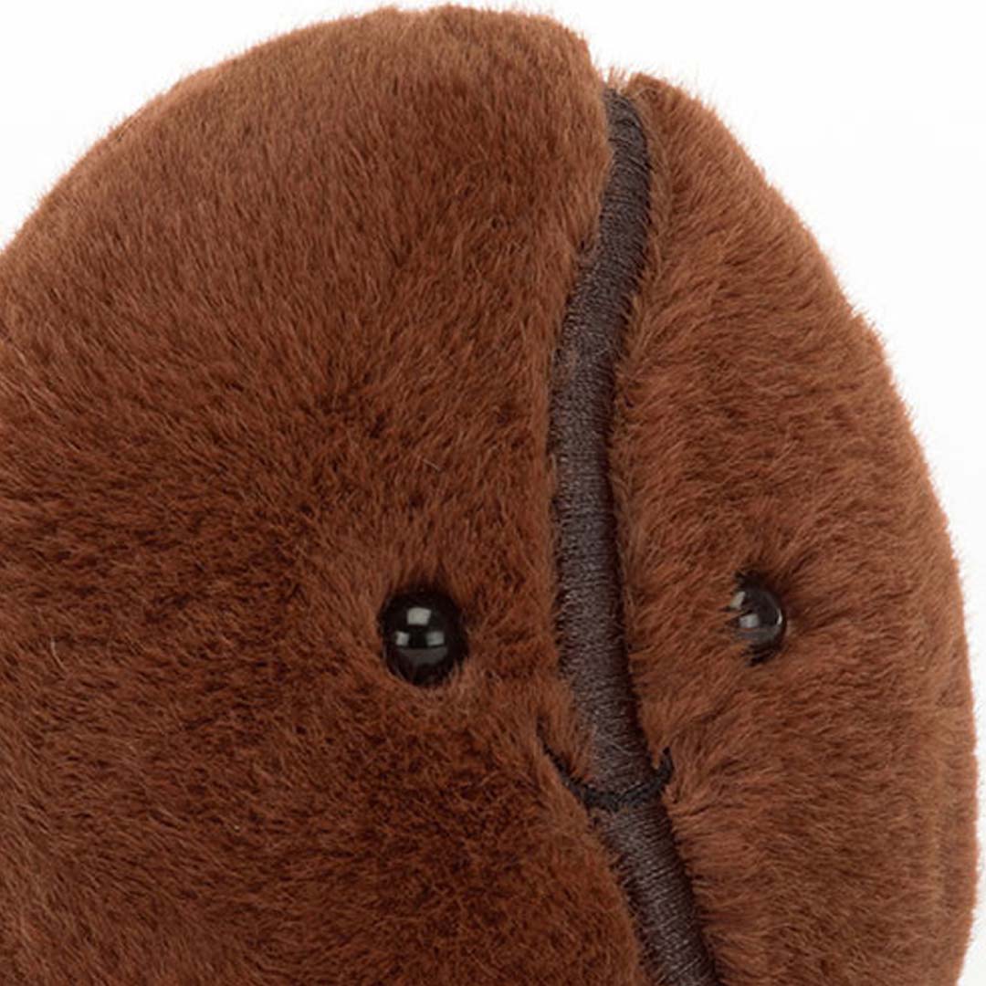 Detailopname van het gezicht van de Jellycat knuffel koffieboon met ogen en glimlach.