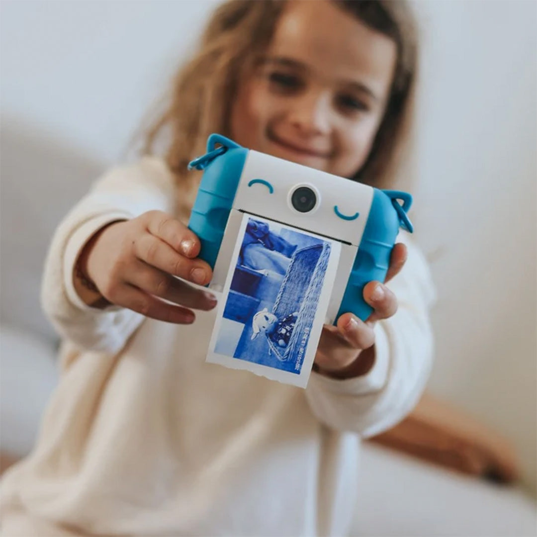 Een kind houdt de blauw-witte kidysnap kindercamera vast die een foto print.