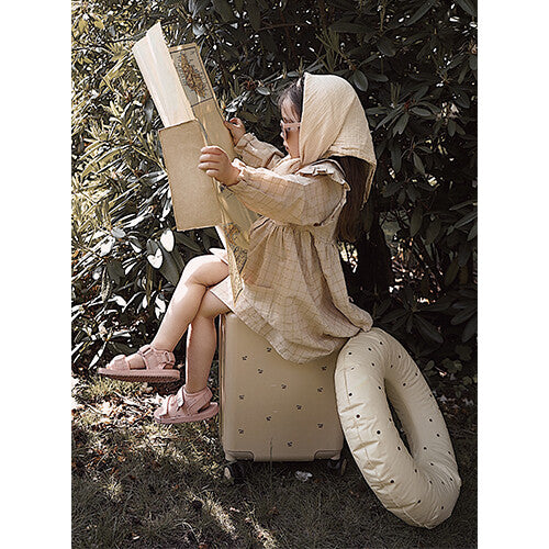 Een kind zit op de Konges Sløjd beige kinderkoffer en leest een kaart.