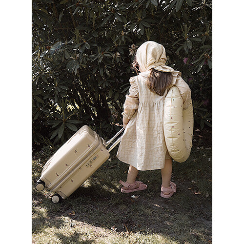 Een kind trekt de Konges Sløjd beige kinderkoffer met uitschuifbaar handvat achter zich aan.