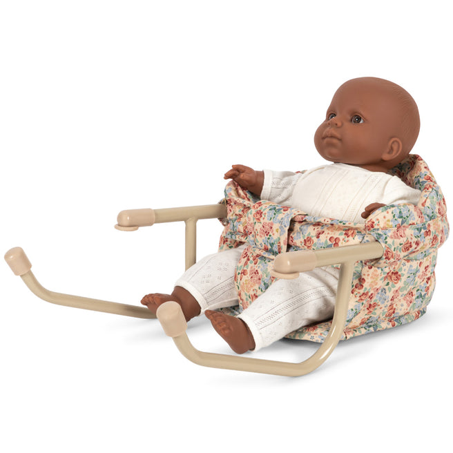 Konges Sløjd poppentafelstoel met gebloemd patroon, waarin een pop met donkere huidskleur zit.