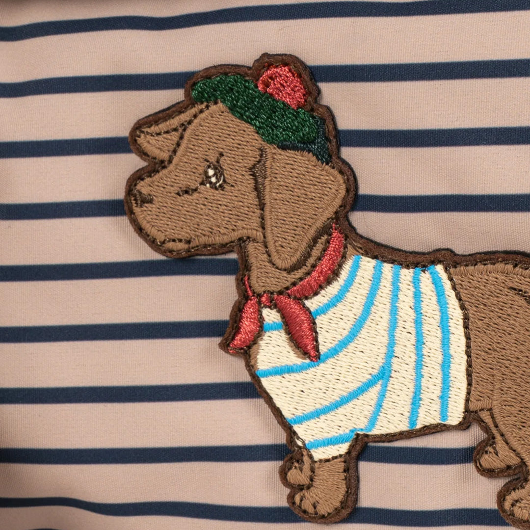 Detail van de geborduurde hond met gestreept shirt en groene muts op de gestreepte peuterrugzak.