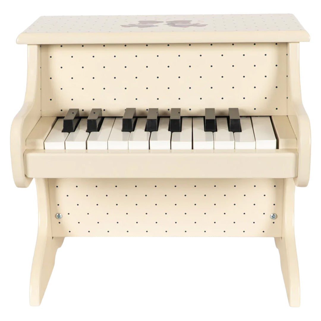 Vooraanzicht van de beige houten speelgoedpiano met zwarte en witte toetsen en een stippenpatroon.