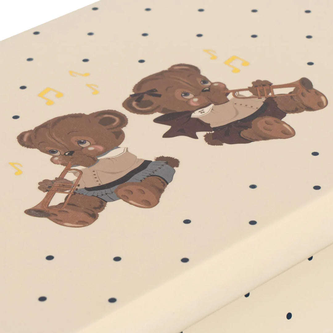 Detail van de beige speelgoedpiano met twee teddyberen die trompet spelen en muzieknoten.
