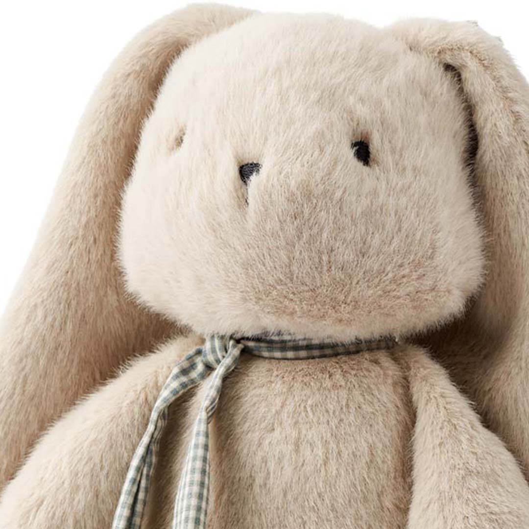 Close-up van het gezicht van het Liewood pluchen knuffelkonijn Berto met lange oren en een geruite sjaal.