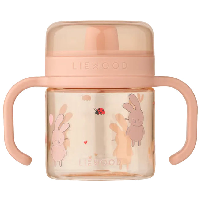Liewood roze tuitbeker met handvatten en een patroon van konijnen en een lieveheersbeestje.