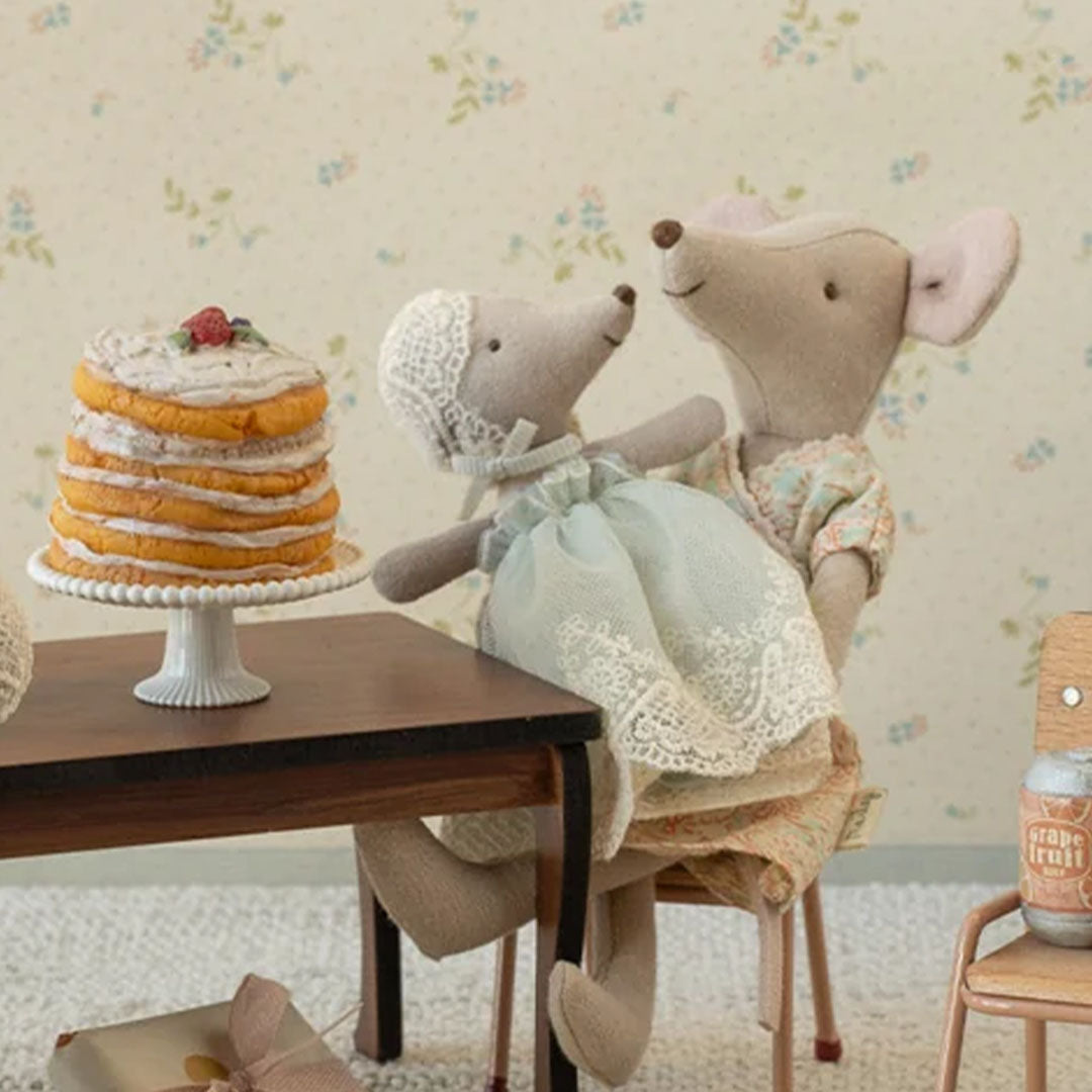 Maileg knuffelmuis in mintgroene nachtjapon zit op schoot bij een grotere muis aan een tafel met pannenkoeken.