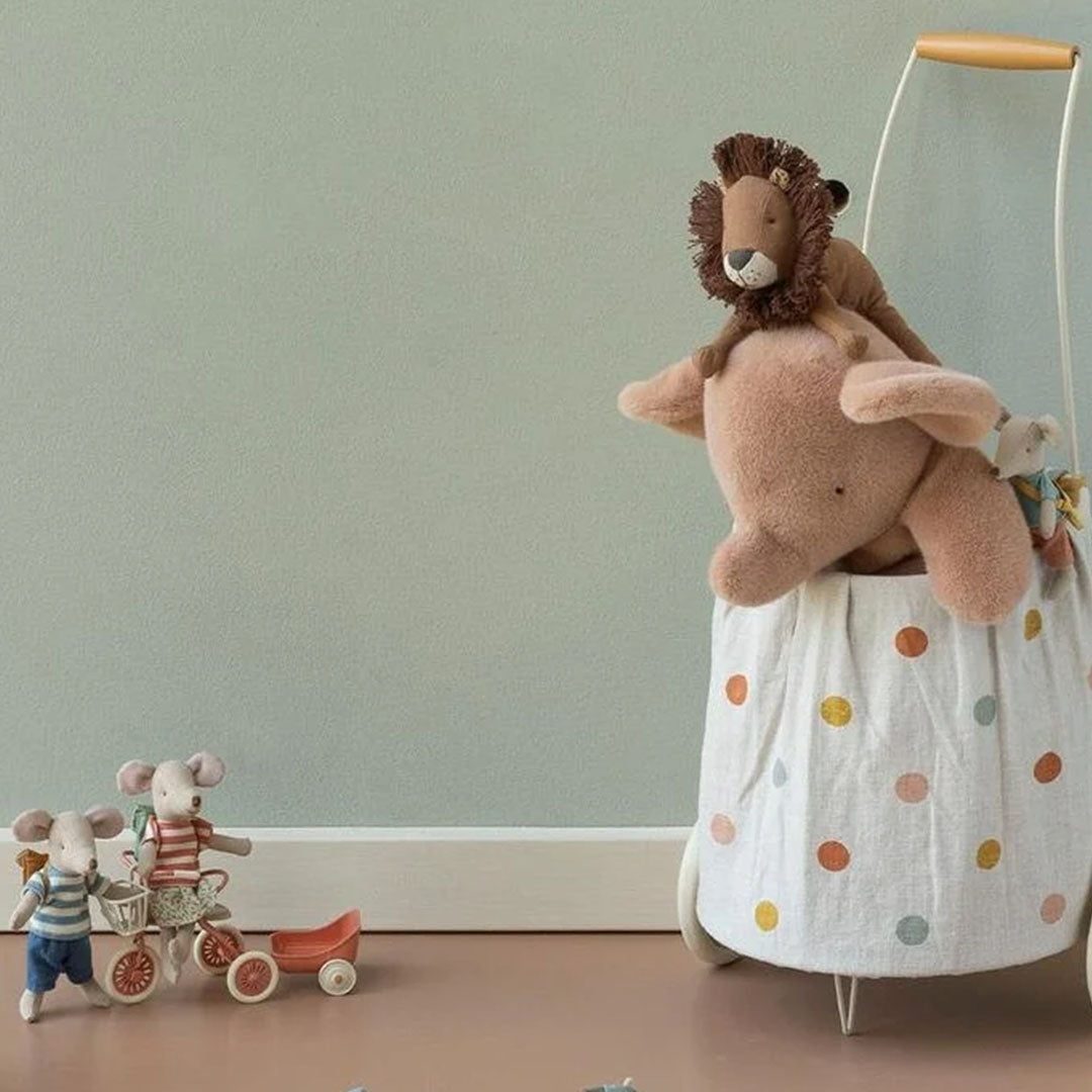 Maileg pluchen knuffelolifant in een speelkamer, zittend in een opbergmand met andere knuffels.