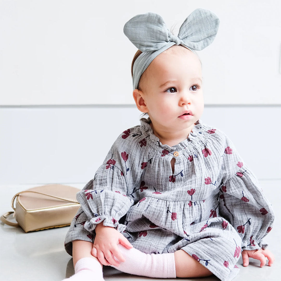 Een baby draagt de Mimi & Lula haarband met strik die op konijnenoren lijkt.