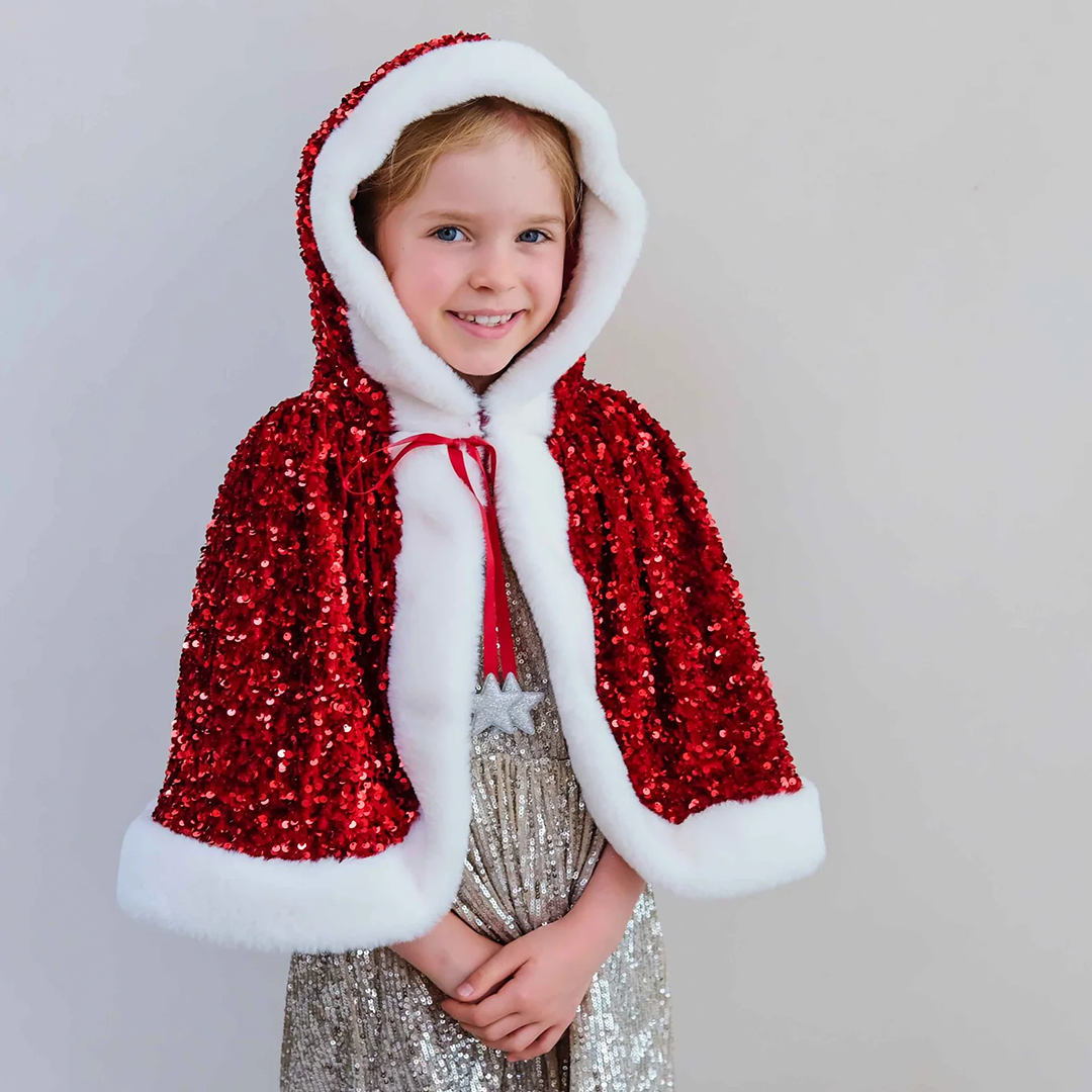 Lachend meisje met blond haar draagt de mimi & lula rode Mrs Claus verkleedcape met pailletten en opgezette capuchon.